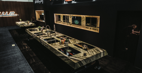 Functional live cooking demonstration island in the BORA booth, showcasing integrated cooktop extractor systems and custom cabinetry for a professional chef experience.