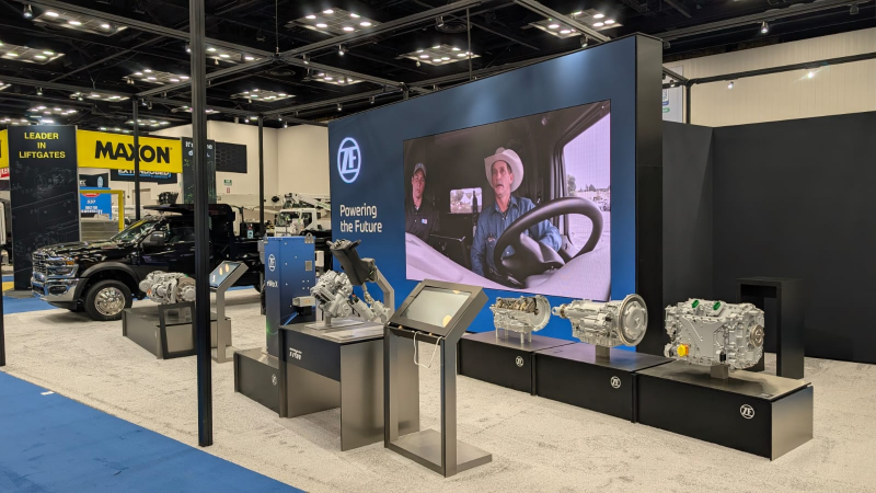 Perspective view of the ZF trade show exhibit from the aisle, showing the spacious layout designed for high-traffic flow and easy access to product demonstrations.